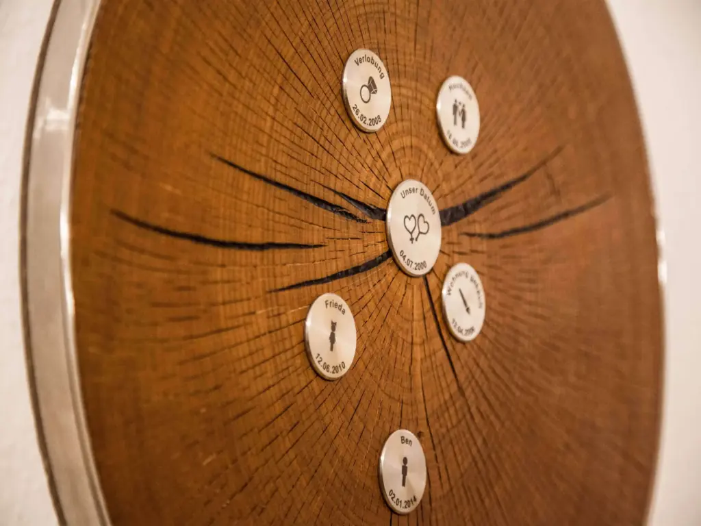 Nahaufnahme gravierter Edelstahl-Meilensteine auf MyLivingTree Baumscheibe — Verlobung, Hochzeit, Kinder mit Datum und Symbol